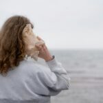 a woman holding a seashell up to her face