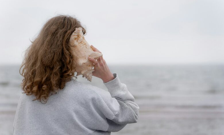 a woman holding a seashell up to her face